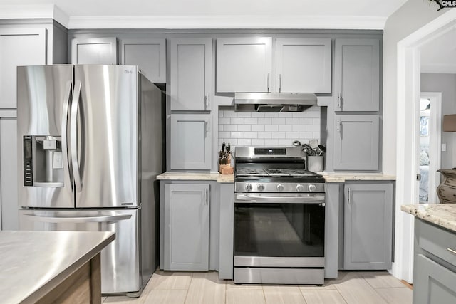 kitchen with decorative backsplash, gray cabinets, exhaust hood, ornamental molding, and stainless steel appliances