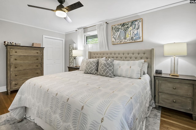 bedroom featuring dark wood-style flooring, ceiling fan, ornamental molding, and a closet