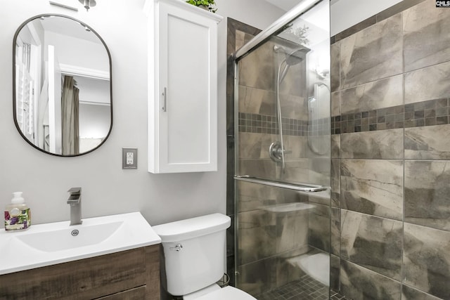 full bathroom featuring vanity, a shower stall, and toilet