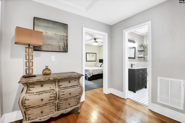 corridor with visible vents, light wood-style floors, and baseboards