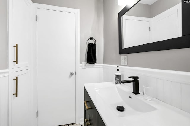 bathroom with a decorative wall, vanity, and a wainscoted wall