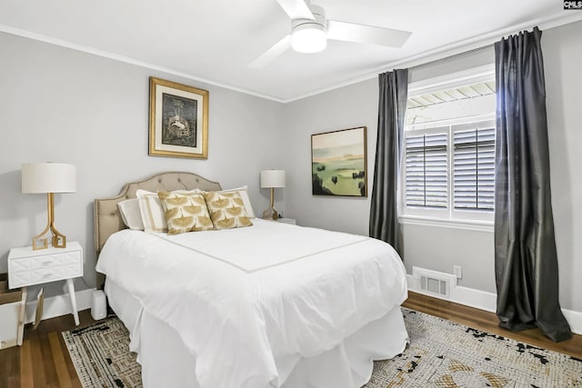 bedroom featuring crown molding, baseboards, wood finished floors, and visible vents