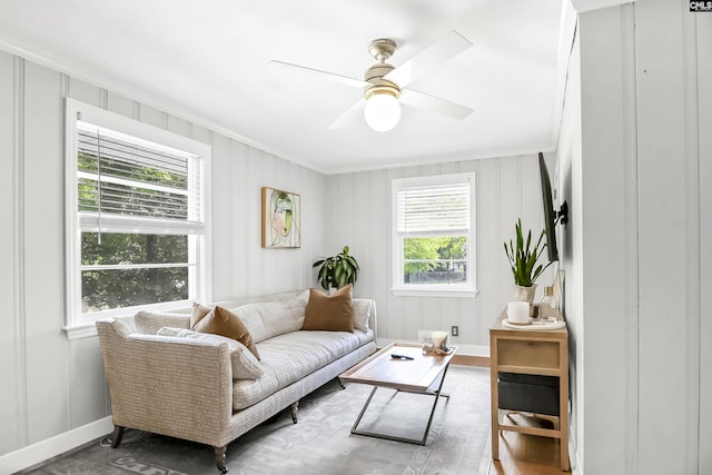 interior space featuring baseboards, ornamental molding, a ceiling fan, and wood finished floors