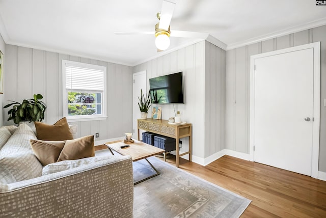 living room with baseboards, ornamental molding, a ceiling fan, and wood finished floors