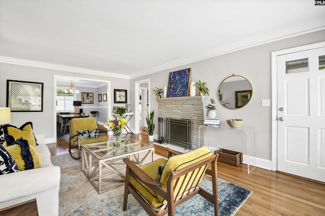 living area with a stone fireplace, ornamental molding, light wood finished floors, and baseboards