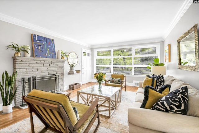 living area featuring crown molding, baseboards, wood finished floors, and a stone fireplace