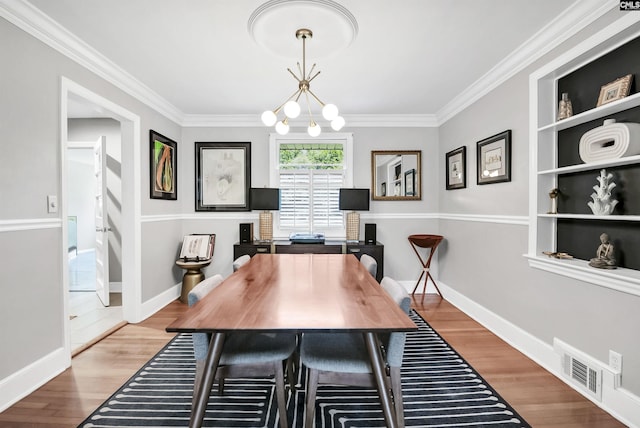 home office featuring crown molding, a notable chandelier, visible vents, and wood finished floors
