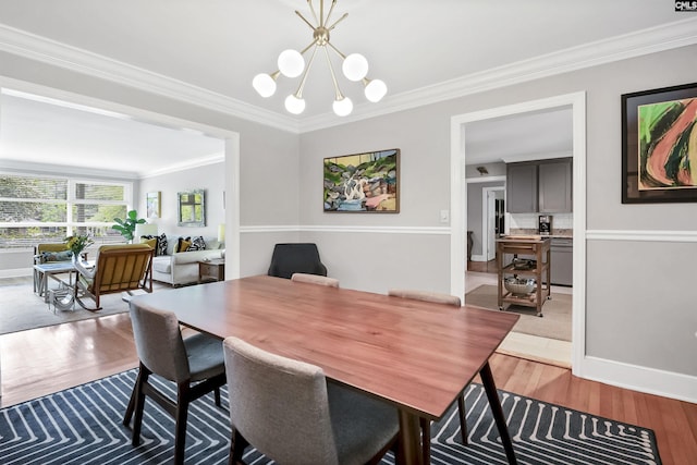 dining area with light wood-type flooring, ornamental molding, and a chandelier