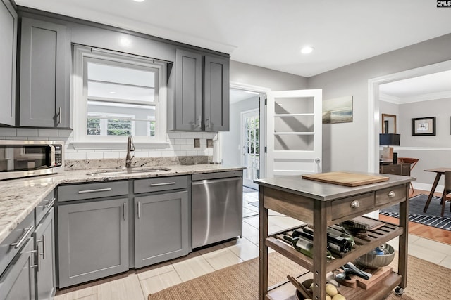 kitchen featuring a sink, stainless steel appliances, decorative backsplash, a wealth of natural light, and gray cabinetry