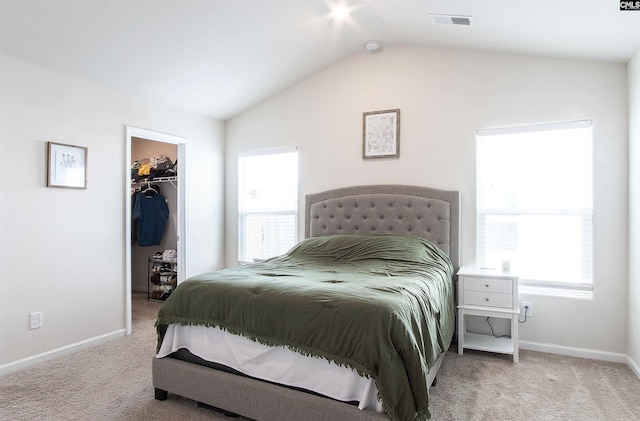 bedroom featuring a walk in closet, carpet, vaulted ceiling, and visible vents