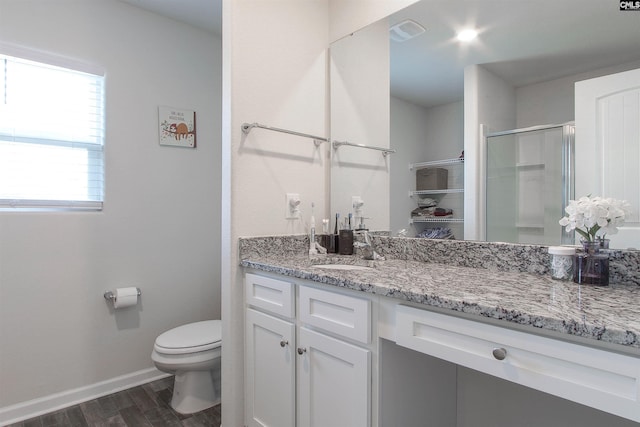 bathroom with vanity, toilet, baseboards, wood finished floors, and a stall shower