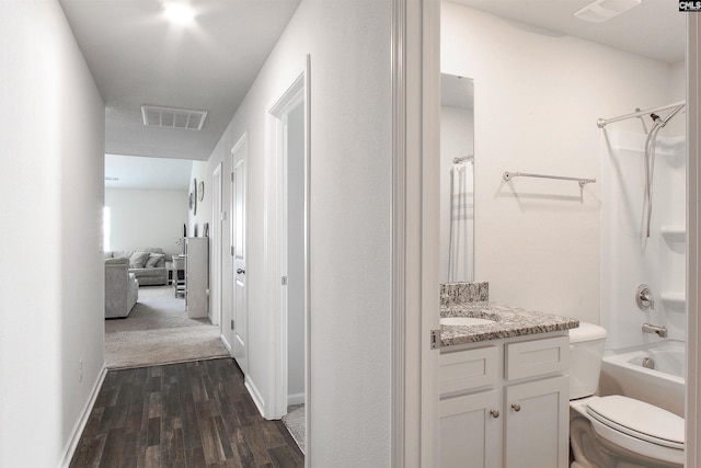 hall with baseboards, visible vents, and dark wood finished floors