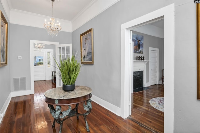 hallway featuring visible vents, ornamental molding, hardwood / wood-style floors, baseboards, and a notable chandelier