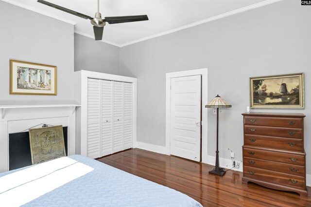 bedroom featuring a ceiling fan, crown molding, a fireplace, wood finished floors, and baseboards