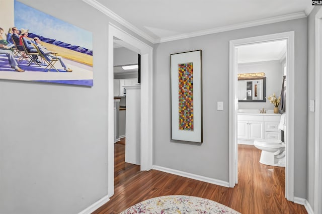 hallway featuring crown molding, baseboards, and wood finished floors