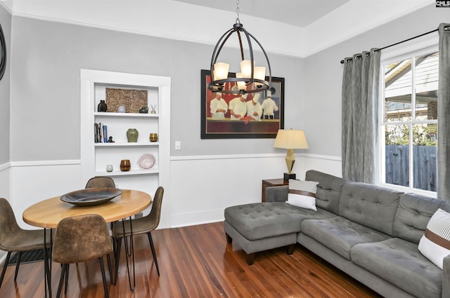 living area featuring an inviting chandelier, built in shelves, and dark wood-type flooring