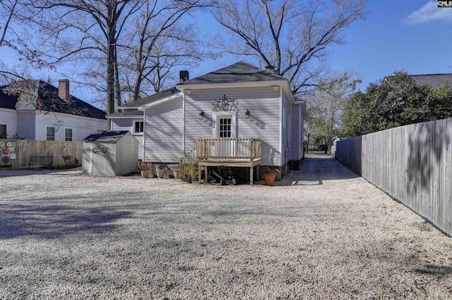 back of property with an outdoor structure, fence, a storage shed, and gravel driveway