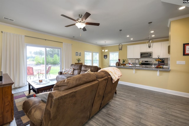 living room featuring crown molding, ceiling fan, visible vents, and dark wood finished floors