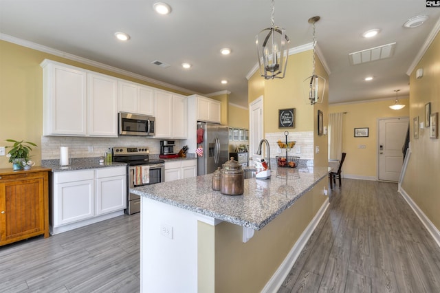 kitchen with crown molding, decorative backsplash, visible vents, light wood-style flooring, and stainless steel appliances
