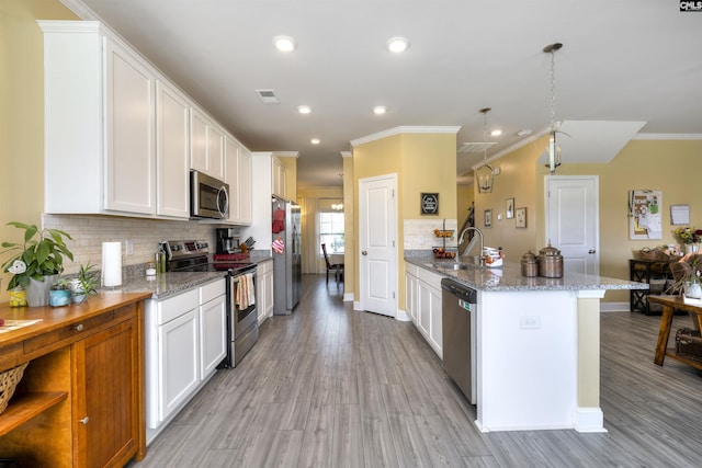 kitchen with crown molding, appliances with stainless steel finishes, a sink, light wood finished floors, and backsplash