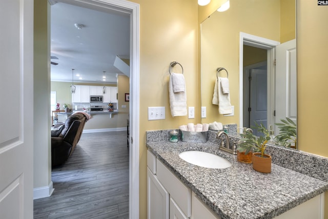 bathroom featuring baseboards, ceiling fan, wood finished floors, and vanity