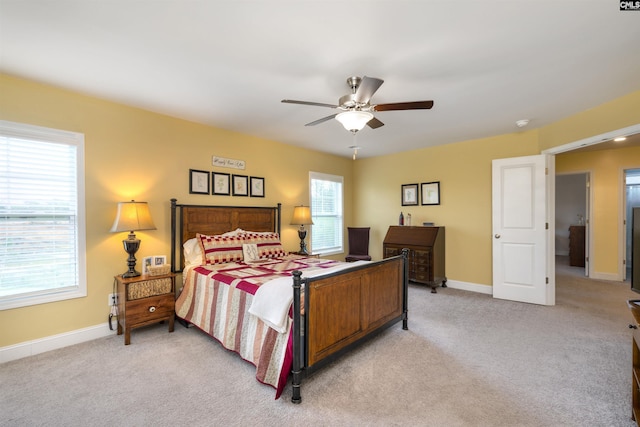 bedroom with light colored carpet, a ceiling fan, and baseboards