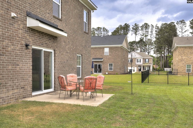 rear view of property with a lawn, brick siding, fence, and a patio