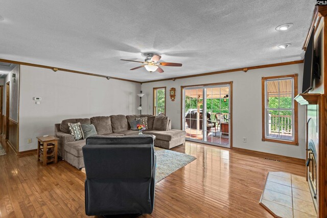 living area with crown molding, a textured ceiling, ceiling fan, and light wood-style flooring