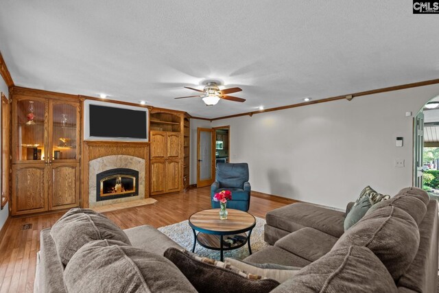 living room with a ceiling fan, arched walkways, ornamental molding, and light wood-style floors
