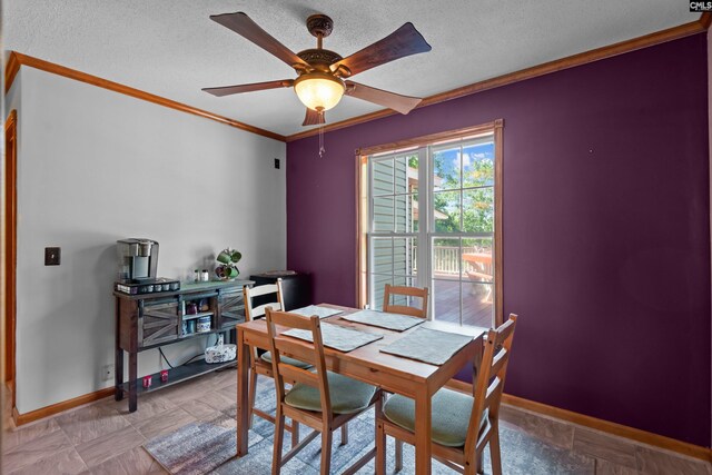 dining room featuring baseboards, ornamental molding, a textured ceiling, and ceiling fan