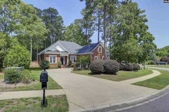craftsman-style home featuring concrete driveway, a front lawn, and brick siding