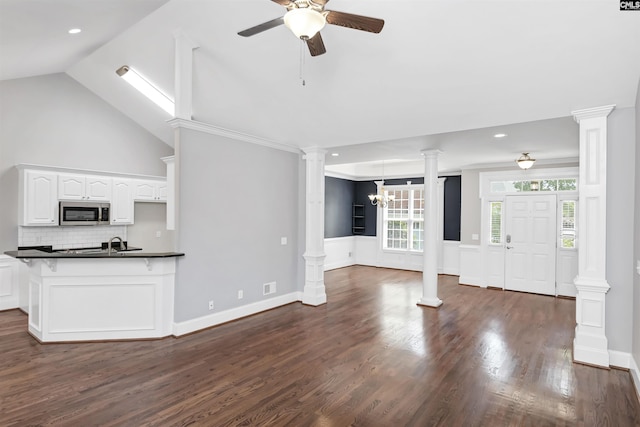 kitchen featuring dark countertops, white cabinetry, stainless steel microwave, tasteful backsplash, and ceiling fan with notable chandelier