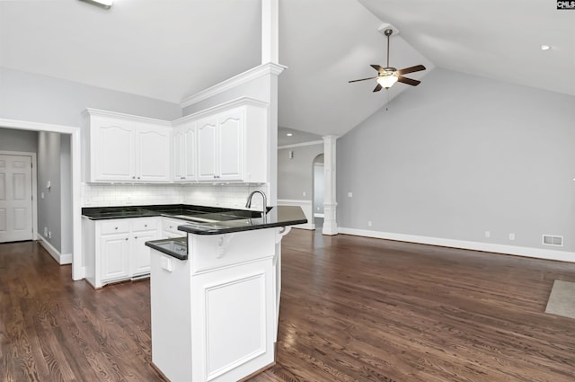 kitchen featuring a kitchen breakfast bar, a ceiling fan, dark countertops, white cabinets, and a peninsula