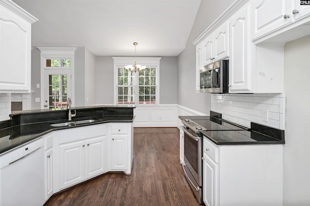 kitchen with dark countertops, dark wood-type flooring, a chandelier, a sink, and stainless steel appliances