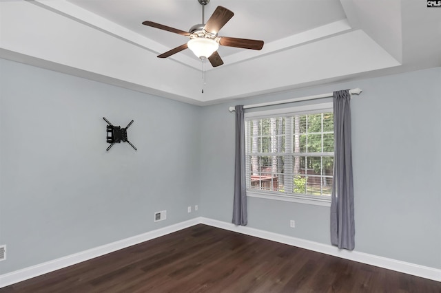 unfurnished room featuring baseboards, a raised ceiling, dark wood-style flooring, and ceiling fan