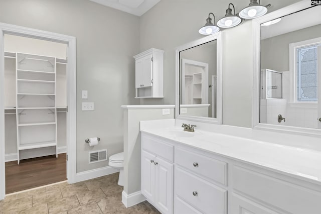 bathroom with visible vents, walk in shower, a spacious closet, and toilet
