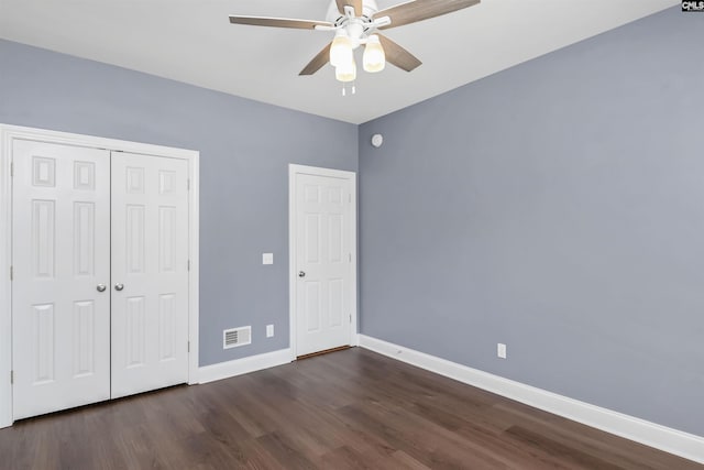 unfurnished bedroom with visible vents, a closet, baseboards, dark wood-type flooring, and a ceiling fan