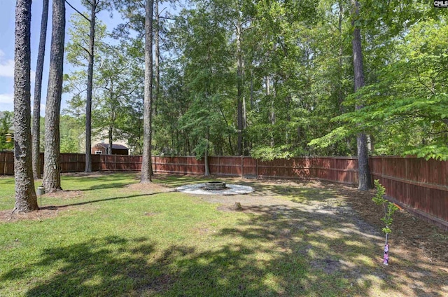 view of yard featuring a fenced backyard and a fire pit