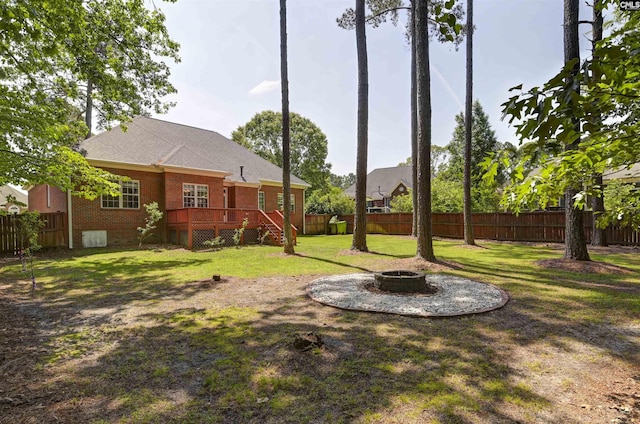 view of yard with a fenced backyard, a fire pit, and a deck