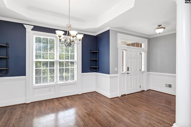 unfurnished dining area with visible vents, decorative columns, dark wood-style flooring, wainscoting, and a notable chandelier