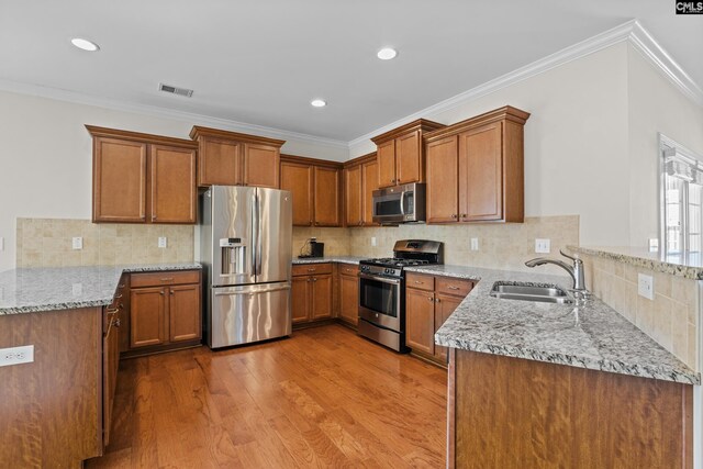 kitchen featuring visible vents, a peninsula, light stone countertops, a sink, and appliances with stainless steel finishes