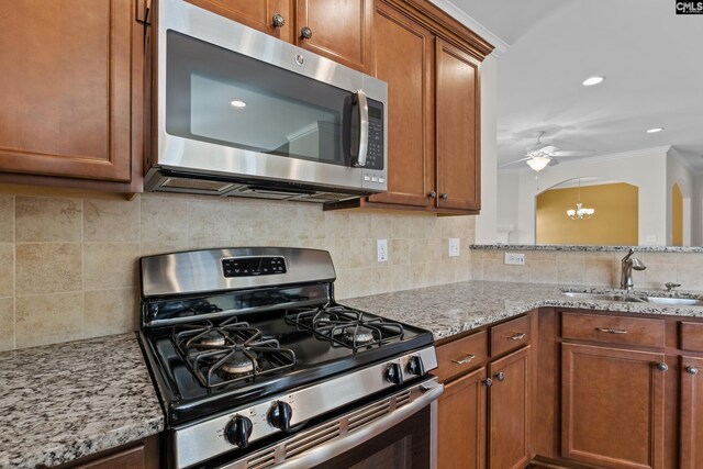 kitchen with light stone counters, appliances with stainless steel finishes, a sink, and tasteful backsplash