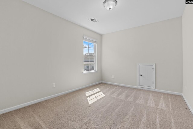 carpeted spare room featuring baseboards and visible vents