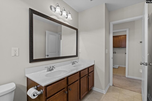 bathroom with a sink, tile patterned flooring, toilet, and double vanity