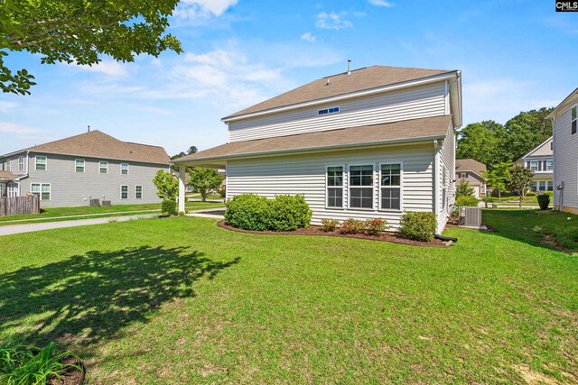 back of property with a yard and central AC