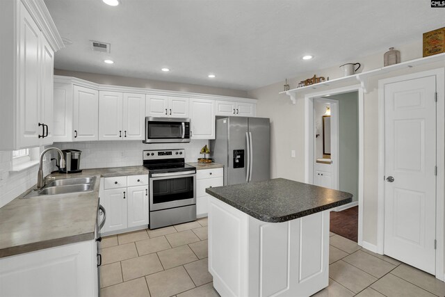 kitchen with a sink, white cabinetry, light tile patterned floors, and stainless steel appliances