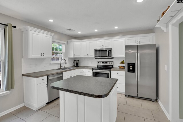 kitchen featuring backsplash, white cabinetry, appliances with stainless steel finishes, and a sink