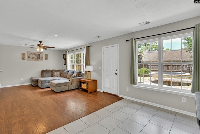 living area with visible vents, baseboards, and ceiling fan