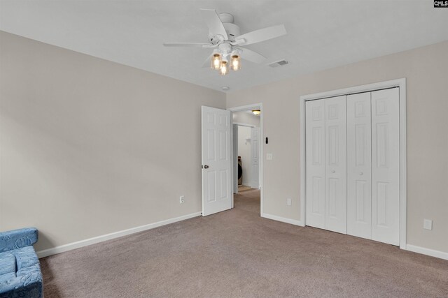 unfurnished bedroom featuring visible vents, carpet floors, a closet, baseboards, and ceiling fan