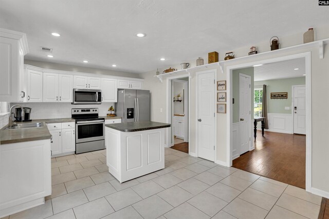 kitchen featuring visible vents, a kitchen island, a sink, light tile patterned floors, and stainless steel appliances